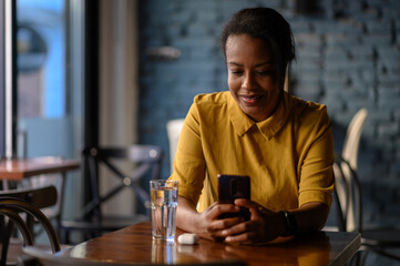 African american woman using a smartphone while sitting in a cafe