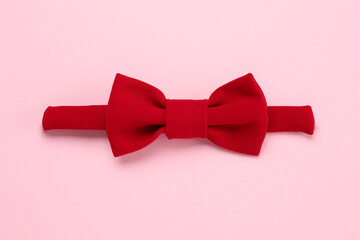 Stylish red bow tie on pink background, top view