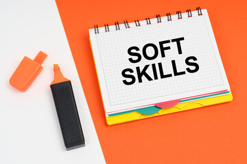 On a white-orange surface lies a marker and a notepad with the inscription - SOFT SKILLS