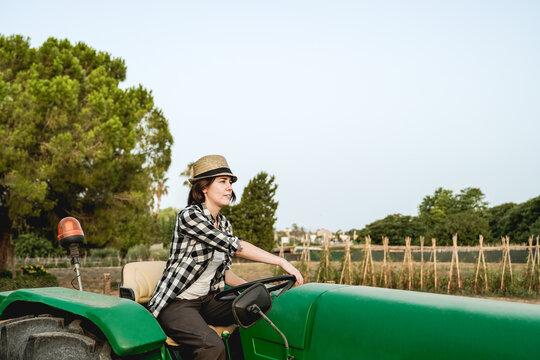Farmer worker woman driving tractor outdoor - Farm lifestyle and harvesting concept - Focus on face