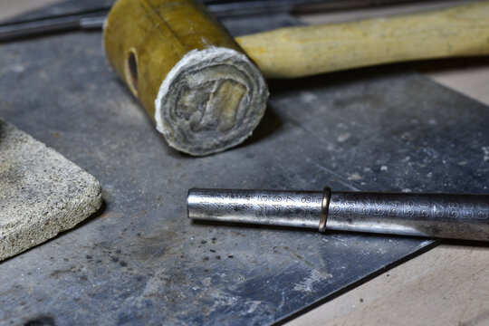 Wedding ring resizing with a jeweler hammer.