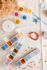 Items for beading - boxes with beads, thread and scissors on the table. Creative leisure, home teaching crafts for children. Top  and vertical view.