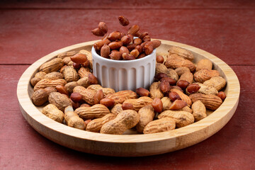 Peanuts falling into a snack bar, on a red wooden table.