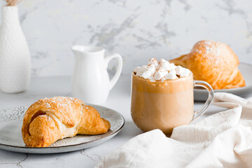 Fresh croissant on a plate and a big cup of coffee on the table. Homemade breakfast lifestyle