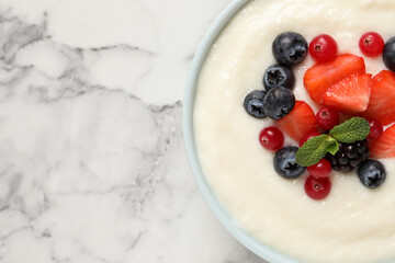 Delicious semolina pudding with berries on white marble table, top view. Space for text