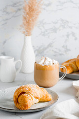 Delicious coffee with marshmallows and croissants on plates on the table. Lifestyle homemade snack. Vertical view