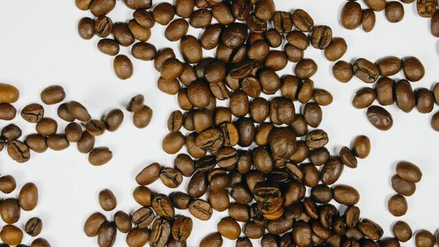 The coffee beans spin rotate quickly fast fly, dispart, splash to the sides with centrifugal coriolis force. The video is in reverse. Twist, create pattern, make design picture. Pressurized air wind.