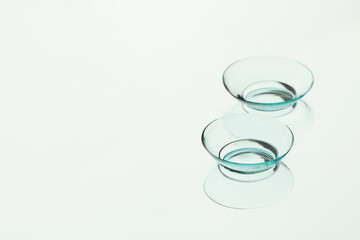 Pair of contact lenses on white reflective surface. Space for text