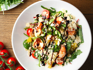 Salad with spinach, arugula, salmon, almonds, balsamic vinegar, cheese. Homemade food. The concept of delicious and healthy food. Wooden background. Top view. To close. Healthy eating. Keto diet