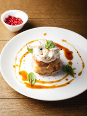 Pork meat in bacon with mushroom sauce, mushrooms. Restaurant serving of a hot meat dish. Hearty food. Lunch for a man. Delicious. Close up. Copy space. Decorated with micro-greens and red pepper peas