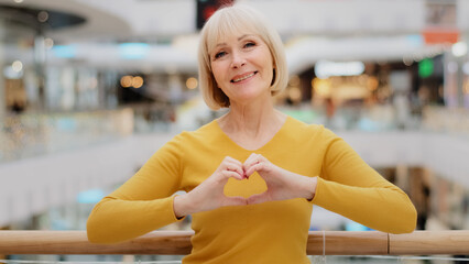 Mature happy caucasian woman standing in public place posing sincerely smiling looking at camera...