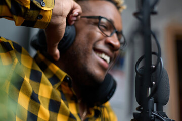 Close-up of an African podcaster blogger smiling while broadcasting his live audio podcast in the...