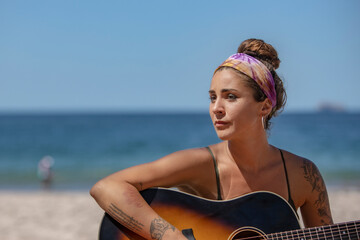 Woman with guitar playing on the beach