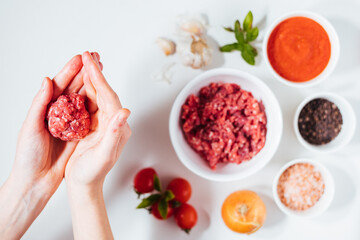 Meatballs in tomato sauce with basil on top. Bright background with ingredients in blurry background. This meal is called Kofte in Turkey and Cufte in Balkans. International meatball day.