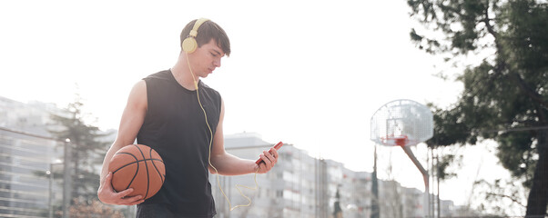 young athlete on a basketball court training while listening to music.