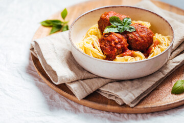 Meatballs in tomato sauce with basil on top. Bright background with ingredients in blurry background. This meal is called Kofte in Turkey and Cufte in Balkans. International meatball day.