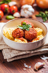 Meatballs in tomato sauce with basil on top. Bright background with ingredients in blurry background. This meal is called Kofte in Turkey and Cufte in Balkans. International meatball day.