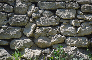 Ancient stone wall. Background of an old antique stone wall composed of stones of early size and shape. ruins of antiquity