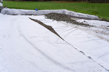 Canvas of white geotextiles on brown soil.