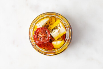 Top view of Glass jar with nature feta cheese and tomatoes in olive oil. Product on white background