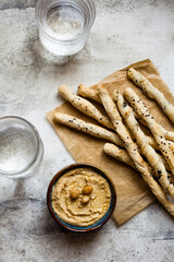 Overhead view of hummus in a bowl with bread sticks
