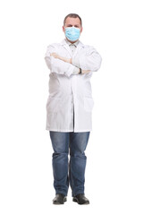 Doctor wearing a surgical mask against infections standing with crossed arms in a lab coat isolated on white