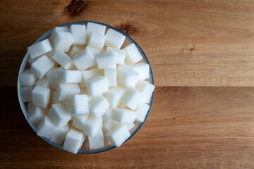 Top view of white sugar cubes in glass bowl,wooden background