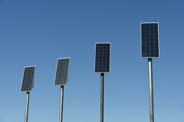 many small solar panels against background of clear blue sky