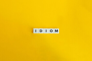 Idiom Word on Letter tiles on bright orange background. Minimal aesthetics. - obrazy, fototapety, plakaty