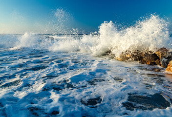 Beautiful Sea Landscape with Waves Breaking on a Sandy and Rocky Beach. Waves on Background. Summer time in Rhodes, Greece. rocks on the coast of blue sea on a sunny summer day