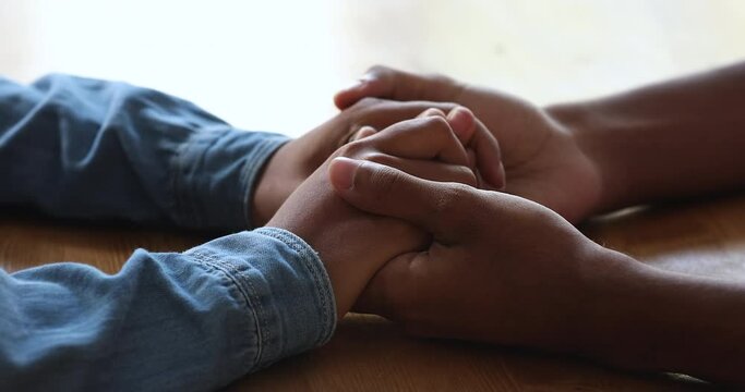 Close up young African couple sit at table holding hands enjoy romantic date. Concept of declaration of love, express support, provide psychological help, empathy, sincere feelings, trust in relations
