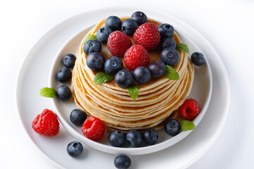 Stack of delicious pancakes with berries and mint leaf on plate isolated on white