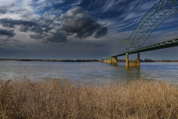 the Memphis–Arkansas Memorial Bridge over the vast flowing waters of the Mississippi river with...