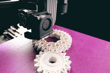 opblique view on process of 3D-printing. print head, bright pink print bed and white helical gears...