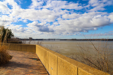 the Memphis & Arkansas Bridge over the vast flowing waters of the Mississippi river with dry brush...