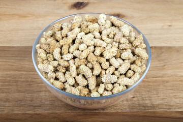 Dried mulberry in glass bowl on wooden background