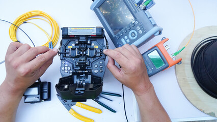 Technician Fiberoptic Fusion Splicing. Worker connecting for Cable Internet signal and Wire connection with Fiber Optic Fusion Splicing machine,fiber optic cable splice machine in work - obrazy, fototapety, plakaty