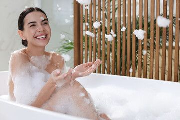 Beautiful young woman taking bubble bath at home