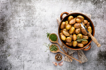 Pan filled with roasted potatoes shot on rustic wooden table.