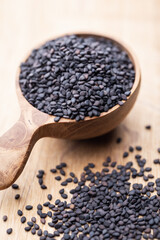 Bio natural black sesame seeds on wooden spoon.