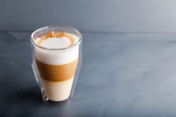 Perfectly gradient latte macchiato view over grey backdrop with copy space.