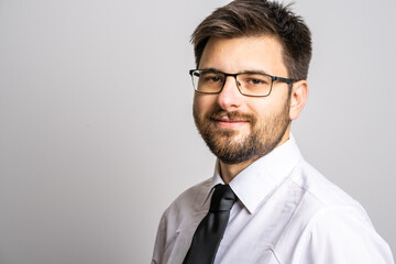 Portrait of one adult caucasian man 30 years old with beard and eyeglasses businessman or doctor looking to the camera in front of white wall background wearing shirt confidence success concept