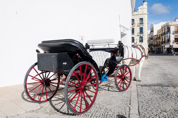 Fototapeta na wymiar La calesa de cabina, carro de caballos delante de plaza de toros: Plaza Teniente Arce, Ronda, provincia de Málaga, Andalucía, España
