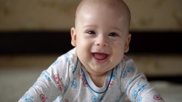 Newborn Active Baby Cute Smiling Teethless Face Portrait Early Days On Stomach Developing Neck Control. 5 Months Child On White Bed Looking on Camera. Infant, Childbirth, Parenthood, Beginning Concept