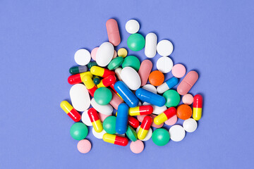 Pile of pills on purple background. Medical background. Pattern made from Various small Pills on bright violet background. Flat lay, top view.