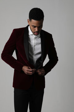 Handsome black man wearing brandy suit posing isolated over grey background.