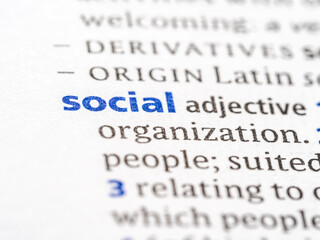 Social - English dictionary definition of the word - photo of a dictionary page with paper grain texture - selective focus on the word
