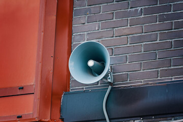 Megaphone hanging on building. City hazard warning system. Loud speaker on brick wall. Providing security in town, notification of emergencies.