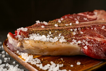 Raw T-bone steak cooking on stone table