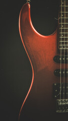 A vintage red electric guitar standing upright with  textured noir concept as wallpaper. Music concept